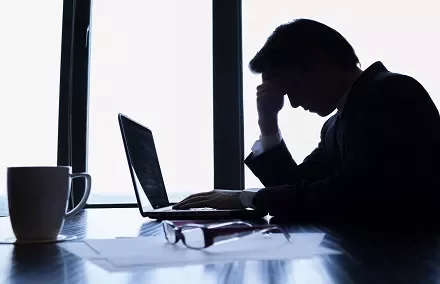 Homem preocupado no trabalho olhando para laptop.