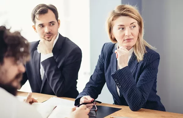 Pessoas em reunião de negócios, algumas olhando para o lado.