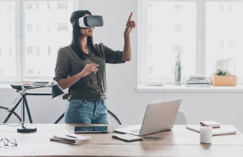 Mulher com óculos de realidade virtual em escritório moderno.