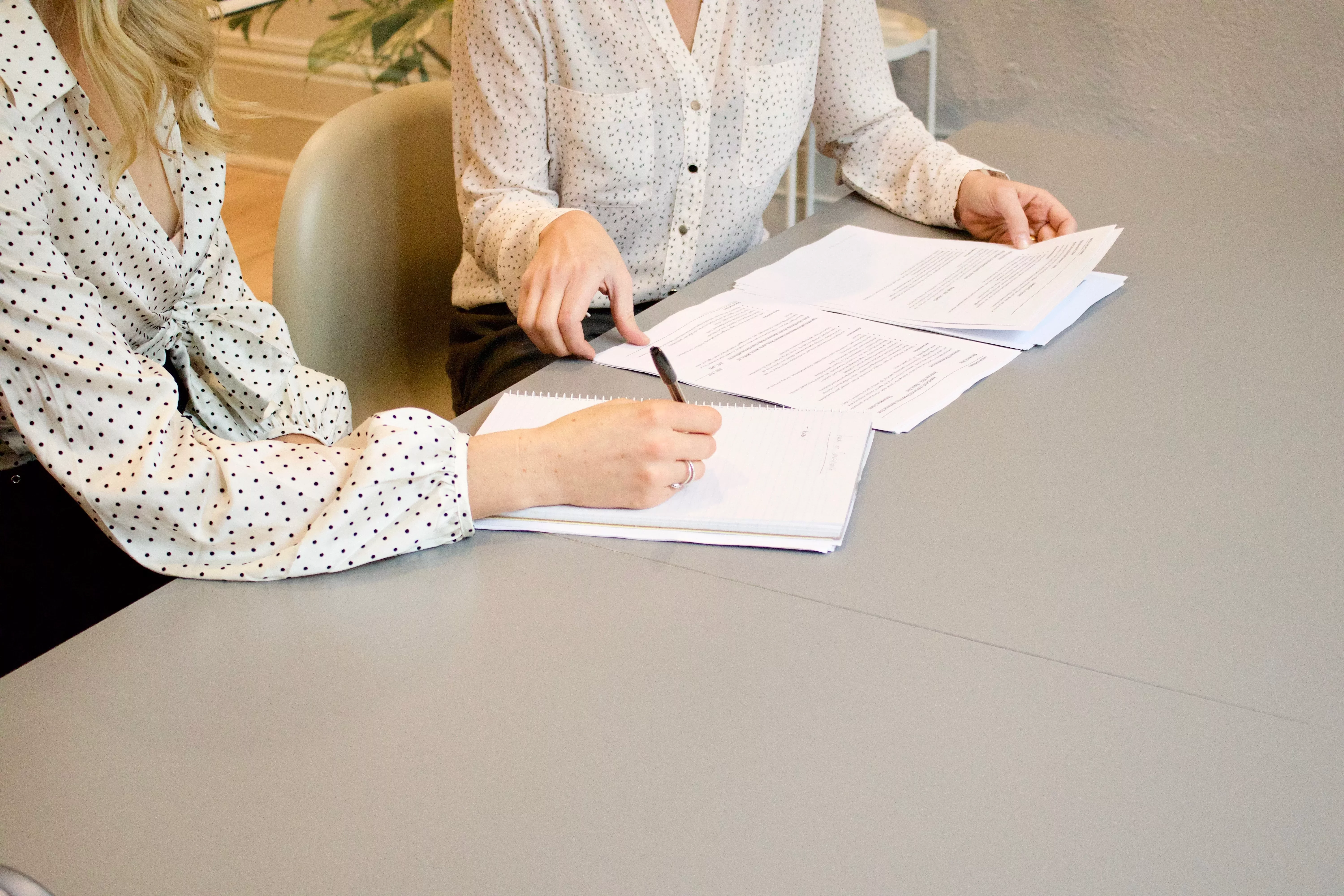 Duas pessoas revisando documentos na mesa.