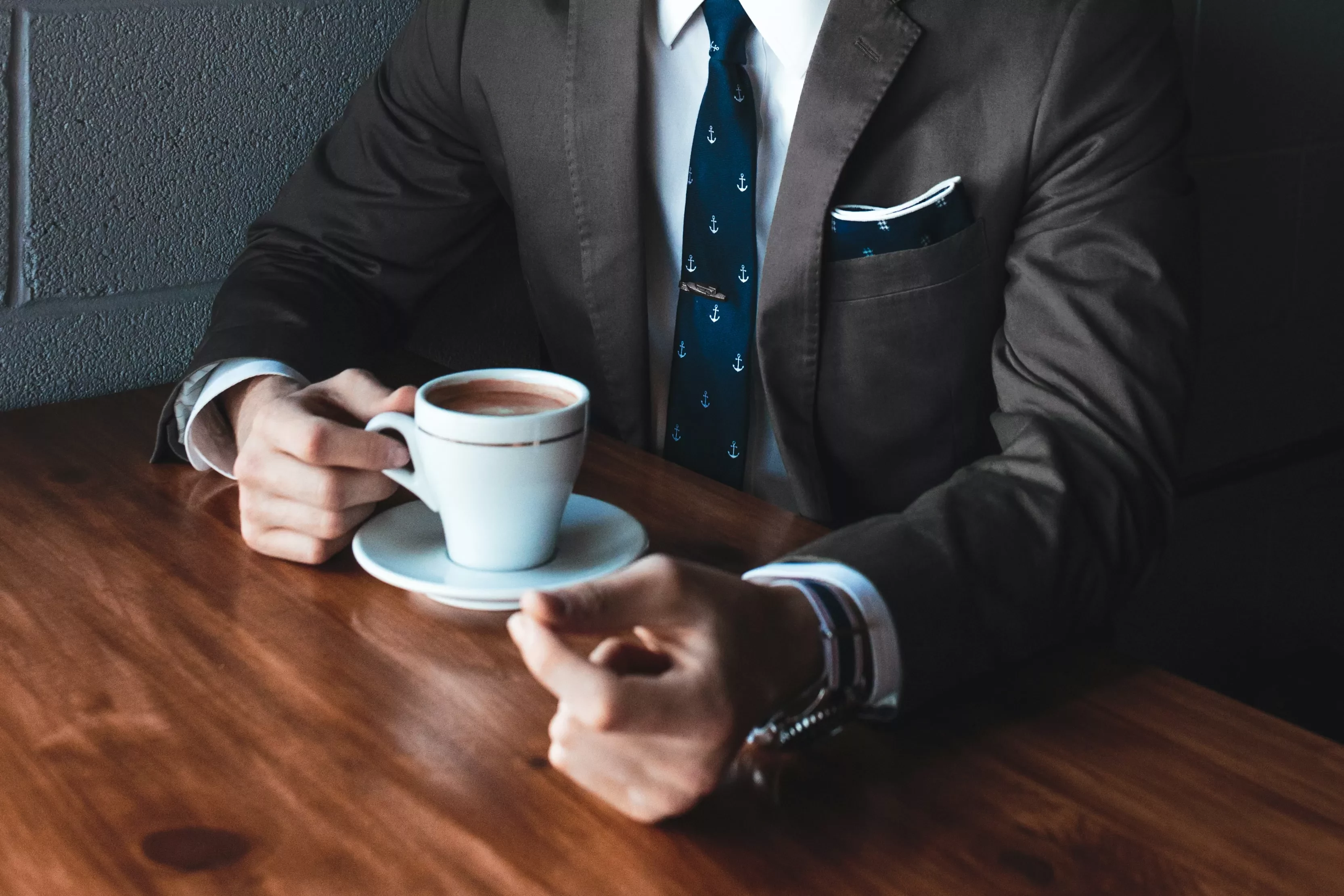 Homem de terno segurando uma xícara de café.