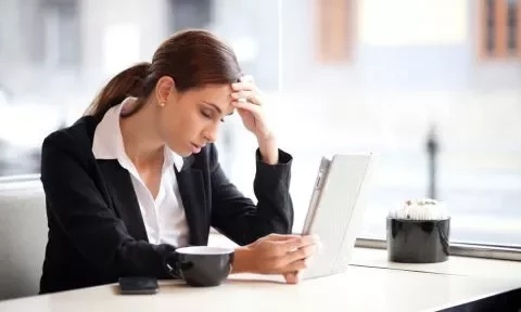 Mulher preocupada olhando para tablet em café.