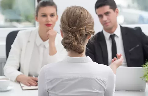 Entrevista de emprego com três pessoas em uma sala de escritório.